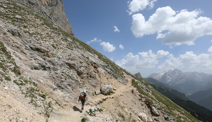 Hiker walking on a rocky trail in the European Alps in Italy during summer