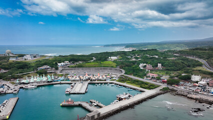 Fototapeta premium Aerial view of a vibrant harbor in Taiwan with boats and lush green hills in the background