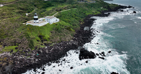 A lighthouse perches on rocky cliffs, overlooking Taiwans turbulent coastal waters