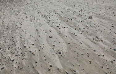 Pebbles on the beach and the marks left by the wind on the grains of sand