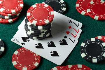 Multicolored chips and playing cards with a combination of four of a kind or quads are randomly...