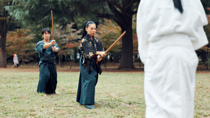 Martial arts, exercise and class instructor with wood sword for fight, battle and samurai training. Park, ninja and mentor with bamboo weapon, kendo and warrior in autumn in Japan with fighter group © Daniels C/peopleimages.com