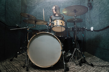 Female drummer performing on professional drum set in soundproof studio, focusing on rhythm and energy of live music creation. Scene highlights passion for music, performance, and artistic expression.