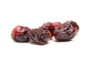 Macro shot of dried cranberries with a shiny, wrinkled texture and vibrant red hues, isolated on a white background. Ideal for food or health themes