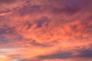 Vibrant sunset sky with fiery orange and pink clouds, illuminated by fading sunlight. Soft textures create a warm, serene, and dramatic scene