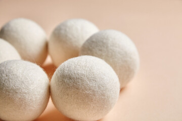 Close-up of wool dryer balls arranged on a soft beige background. Eco-friendly, reusable laundry accessory for reducing static, wrinkles, and drying time