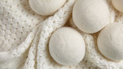Wool dryer balls placed on a textured white knitted blanket, offering an eco-friendly, reusable...