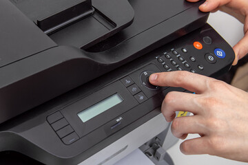 Man presses buttons on the panel of a printer or scanner