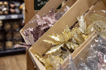 Artificial golden and pink flowers in the store for Christmas home decoration. Decorations for the Christmas tree in wooden boxes. Soft focus