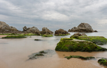 Unique rock formations in the sea water. The water is calm and the rocks are green from algae. Silk effect. Girona, Spain.