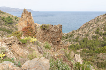 A rocky hillside overlooking a body of water. The view is serene and peaceful, with the ocean in the distance and the rocks providing a sense of stability and strength. Girona, Spain