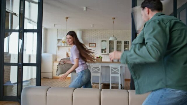 Laughing lovers having fun home closeup. Happy couple fighting pillows playing