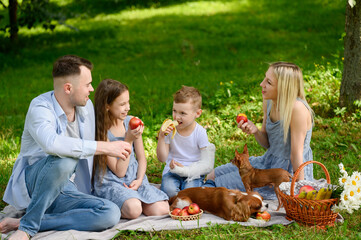 Cheerful family enjoy delightful picnic in park, spending time together with beloved dog next to...