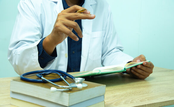 Doctor is documenting a patient's information. The physician, in the white medical coat is filling out a medical record form during a consultation in the clinic.