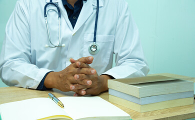 Doctor is documenting a patient's information. The physician, in the white medical coat is filling out a medical record form during a consultation in the clinic.