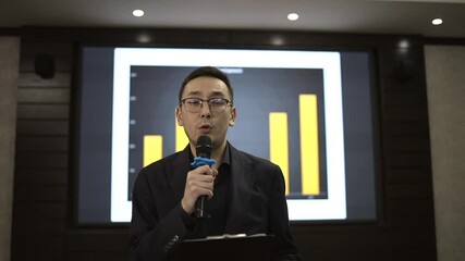 Male presenter engages the audience with insights on company growth, highlighting key metrics on a large display in a contemporary setting.