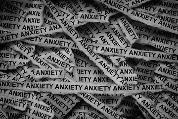 Strips of newspaper with the words Anxiety typed on them. Black and white. Close up.