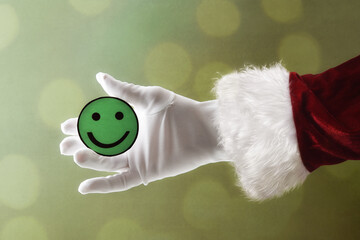 Santa Claus hand holding green smiley face cutout isolated background