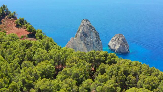 Dream beach revealing video. Aerial tilt view of Greece Limni Keri rock island. Mizithres limestone formation in turquoise clear blue water with white sands and green forest on cliffs in Zakynthos