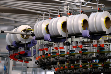 Sewing production, fabric production. Fabric production equipment: huge spools with threads spin...
