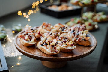 A beautifully crafted wooden plate that is generously topped with an assortment of delicious food items, elegantly arranged on a stylish table, creating a pleasing visual feast