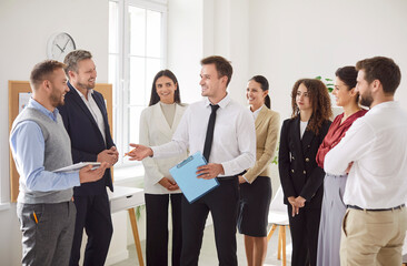 Group of business people chatting on a meeting standing in circle in office. Company employees...