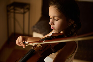 Young girl playing violin with concentration and passion