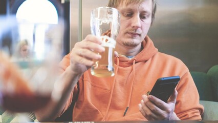 Close-up of man using smartphone while drinking beer in pub.