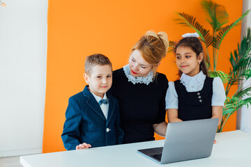 Fototapeta premium Teacher and boy with girl school children with laptop at school