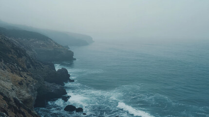 Misty coastal landscape with gentle waves lapping against rocky shore, creating serene atmosphere. fog adds sense of tranquility to scene