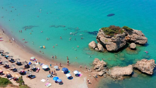 People in Greece at beautiful beach. Aerial drone video from above. Porto Zorro Beach Greek island of Zakynthos. Sun umbrella parasols and sunbeds