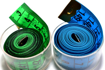 Blue and green measuring tapes for cutting and sewing lie on a white background.