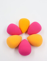 pink and orange Cosmetic sponges on light wooden background, close up
