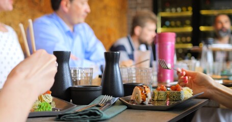 Modern dining with Japanese cuisine. Group enjoying Japanese cuisine with sushi rolls served fresh on table. Harmony of taste and presentation makes this moment ideal for sharing culinary delights.