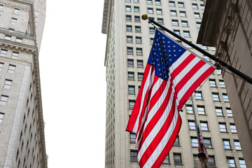 American flag against Wall Street buildings and bright sky
