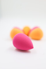 pink and orange Cosmetic sponges on light wooden background, close up
