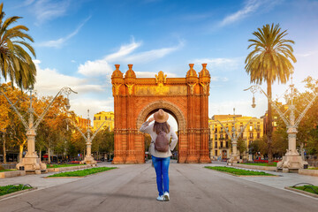 A tourist woman looks at the famous Arc de Triomf in Barcelona, Spain, on her sightseeing trip...