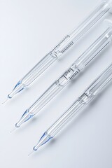 A precise arrangement of glass pipettes and burettes on a flat, reflective white background. 