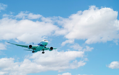 The plane in the sky goes to the landing on runway against a white fluffy clouds in sunny day.Overhead view.