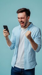 A man in his thirties, wearing a blue shirt and white t-shirt, is excitedly looking at the phone he's holding while standing on a light solid color background