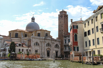 Naklejka premium Side view of old Church San Geremia and stone tower from sailing tourboat on Grand Canal in a sunny summer day in Venice, Italy. Soft focus. Religious architecture. Travel in Italy theme.
