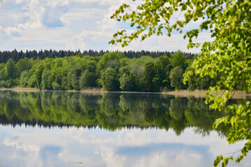 Obraz premium A tranquil lake, beautifully reflected in its clear surface, is surrounded by vibrant greenery