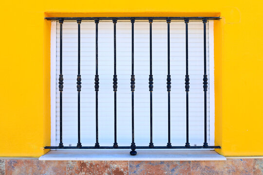 Yellow facade with window and wrought iron railing