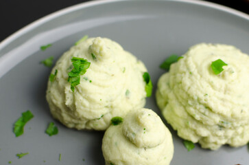 Homemade cauliflower puree on a grey plate, close up, top view
