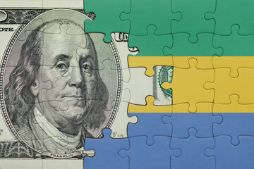 puzzle with the national flag of gabon and the usa dollar money .finance concept