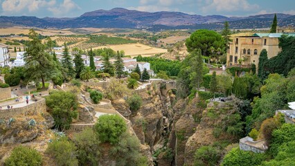 Puente Viejo bridge in Ronda, with several terraces and viewpoints, with fields and mountains in the background