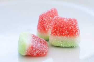 studio shot of three watermelon slices made of sugared gummy on a clean white background. Concept of sweet colorful and luminous world, diabetes, whim and excess sugar