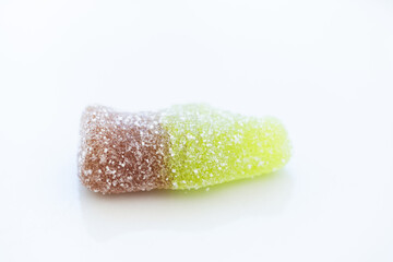 detail studio shot from above a small cola bottle made of jelly beans with sugar on top. It is on a clean white background. Concept of sweet eating, cute things and excess sugar