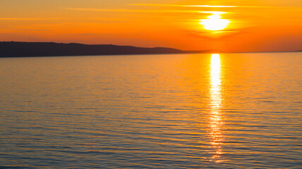 Pôr do sol deslumbrante no mar Mediterrâneo, com as cores quentes do céu refletindo na água tranquila, criando uma atmosfera relaxante e serena ao final do dia