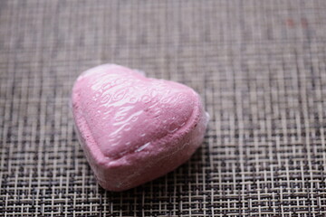 A pink heart shaped candy sitting on a table, perfect for romantic getaways or Valentine's Day celebrations.